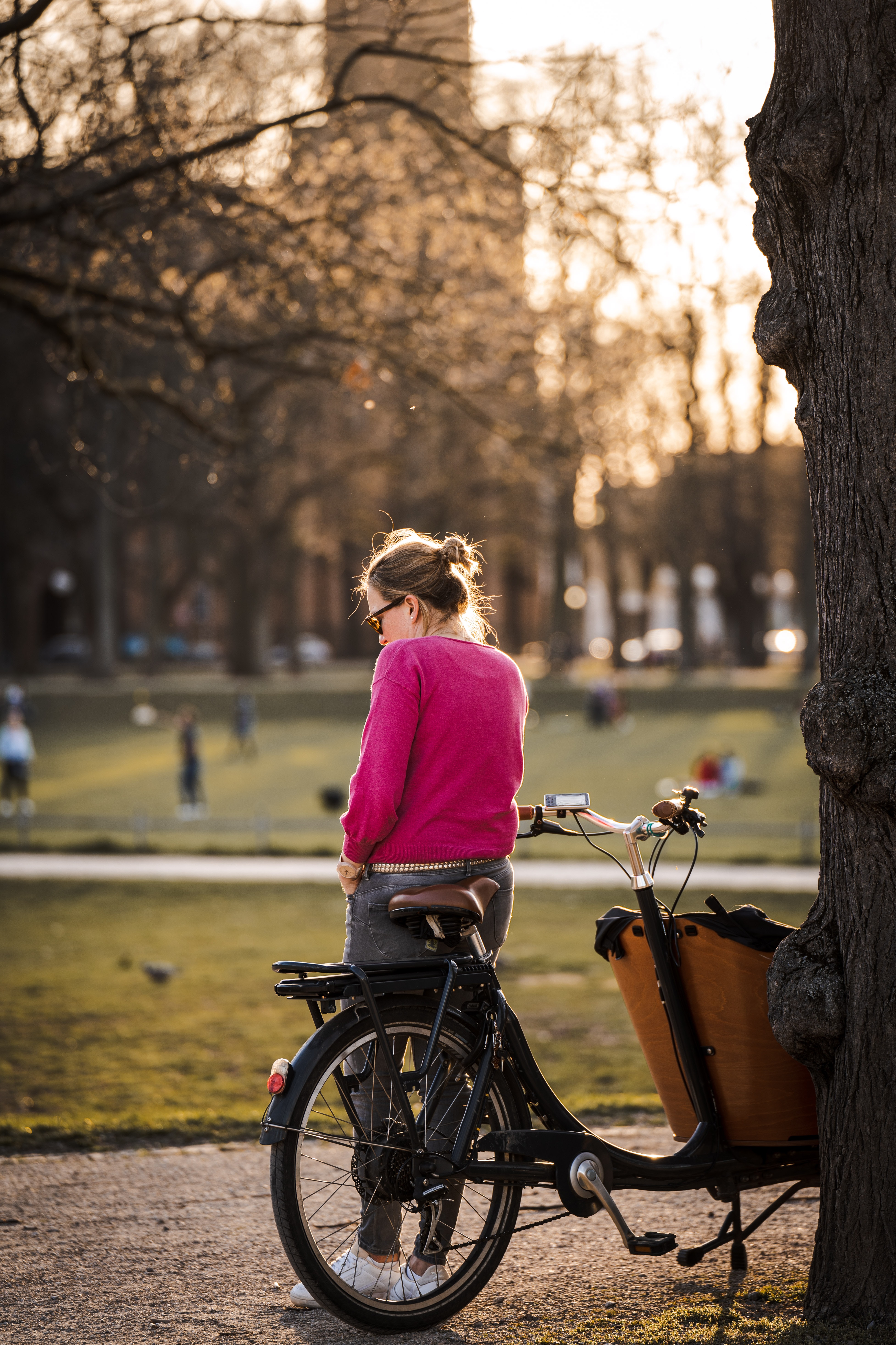 A woman using her phone right next to her cargo bike